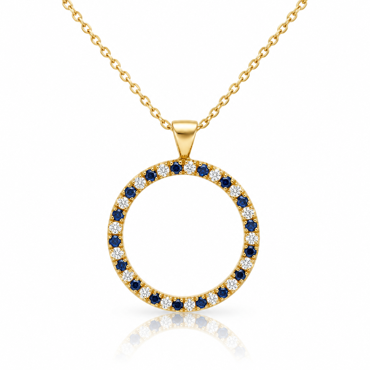 Zawieszka Sapphire Circle wykonana ręcznie w naszej pracowni z żółtego złota, ozdobiona naprzemiennie oprawionymi szafirami i diamentami. Okrągła, otwarta forma tworzy lekką kompozycję, a połączenie intensywnego granatu szafirów z jasnymi diamentami pięknie podkreśla rytm kamieni rozmieszczonych wokół całej zawieszki.